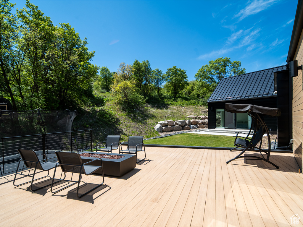 Wooden terrace with an outdoor fire pit and a yard
