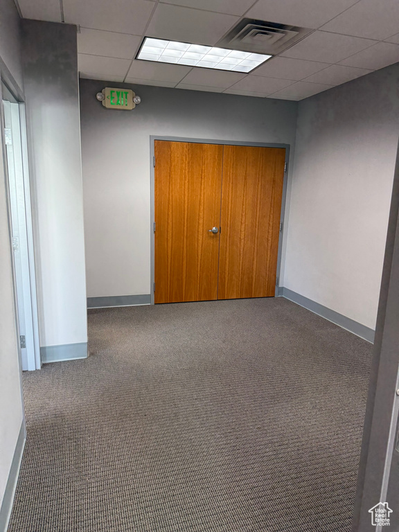 Carpeted spare room featuring baseboards, visible vents, and a paneled ceiling