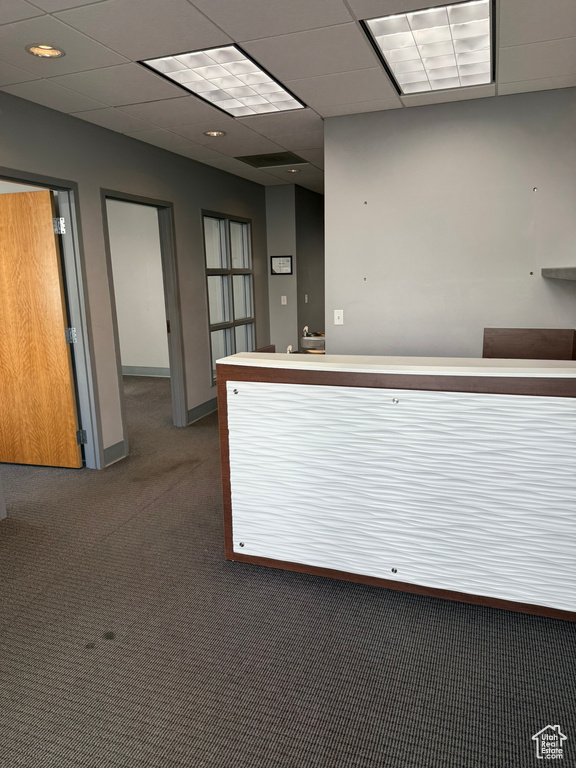 Carpeted spare room featuring baseboards, a community bar, a drop ceiling, and visible vents