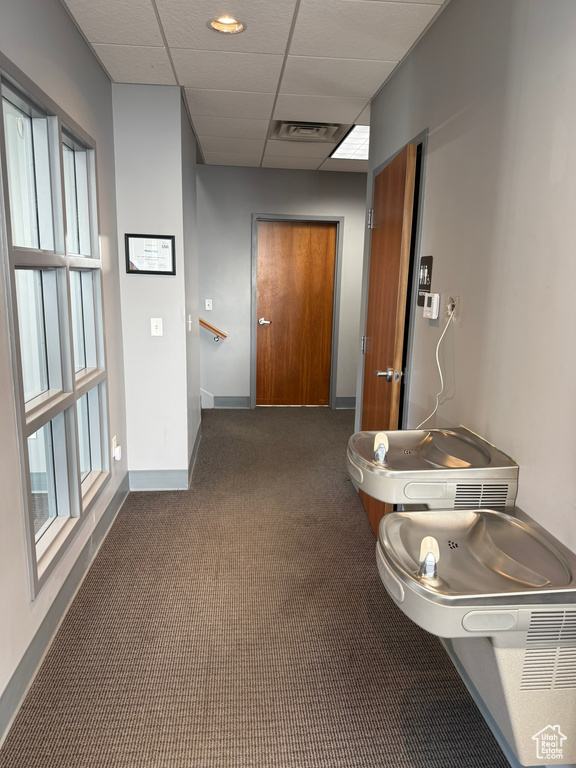 Corridor with carpet floors, baseboards, visible vents, and a paneled ceiling