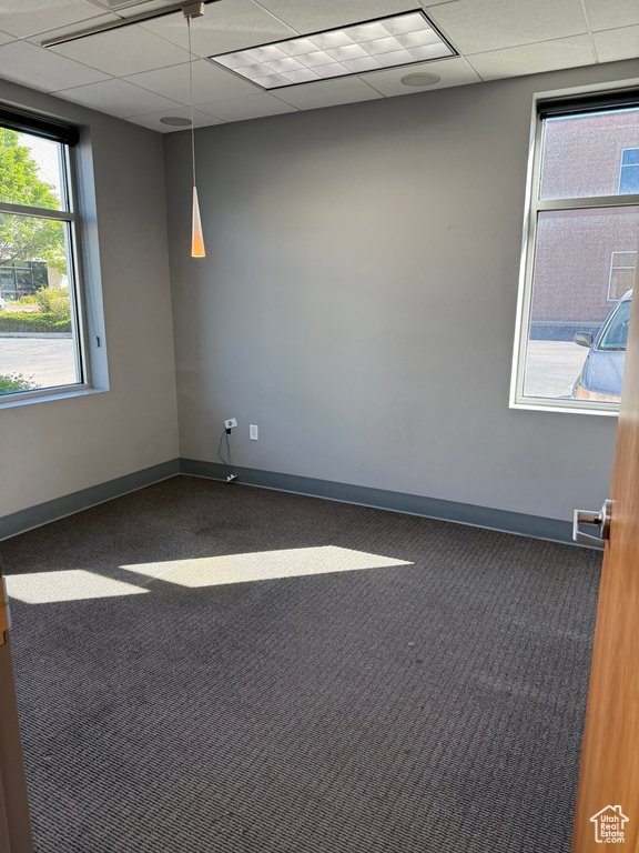 Carpeted empty room featuring baseboards and a paneled ceiling