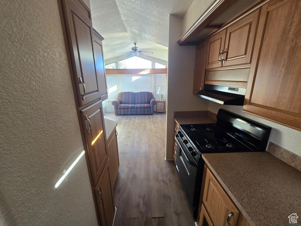 Kitchen featuring dark wood-type flooring, black range with electric cooktop, extractor fan, a textured ceiling, and lofted ceiling