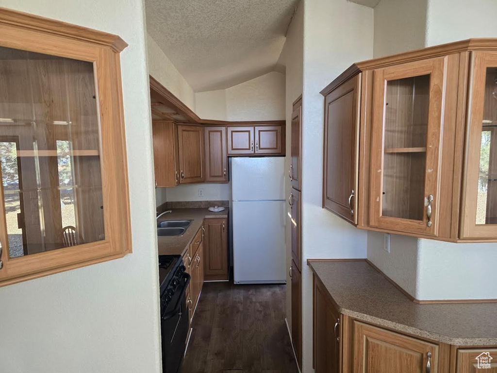 Kitchen with black range oven, sink, white fridge, dark hardwood / wood-style floors, and lofted ceiling