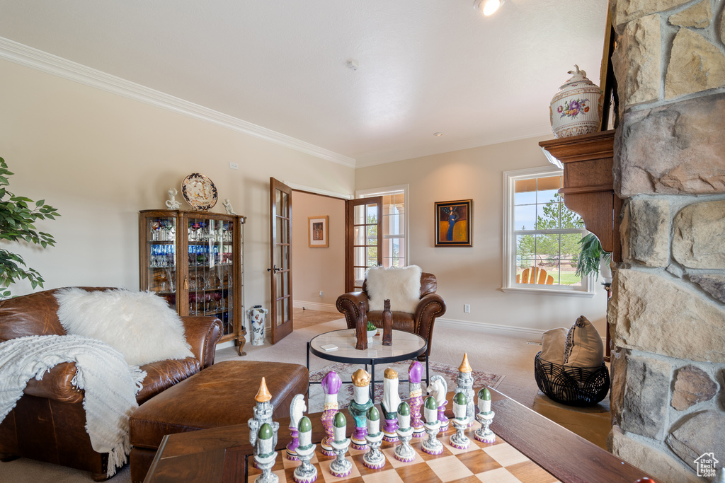 Living room with carpet flooring, ornamental molding, a stone fireplace, and french doors