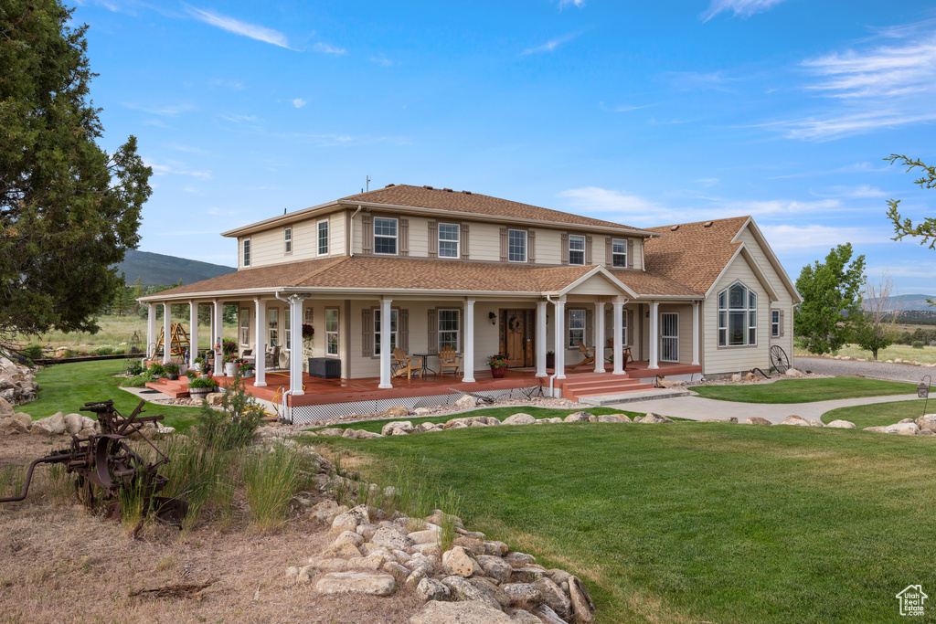 Farmhouse with covered porch, a front lawn, and roof with shingles