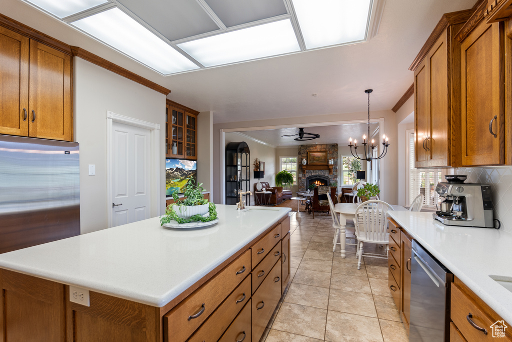 Kitchen with brown cabinetry, stainless steel appliances, tasteful backsplash, and open floor plan