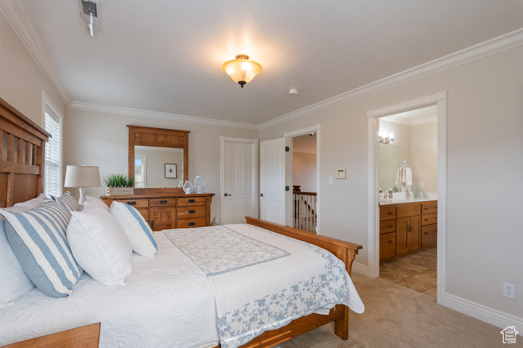 Bedroom with ornamental molding, light colored carpet, and connected bathroom