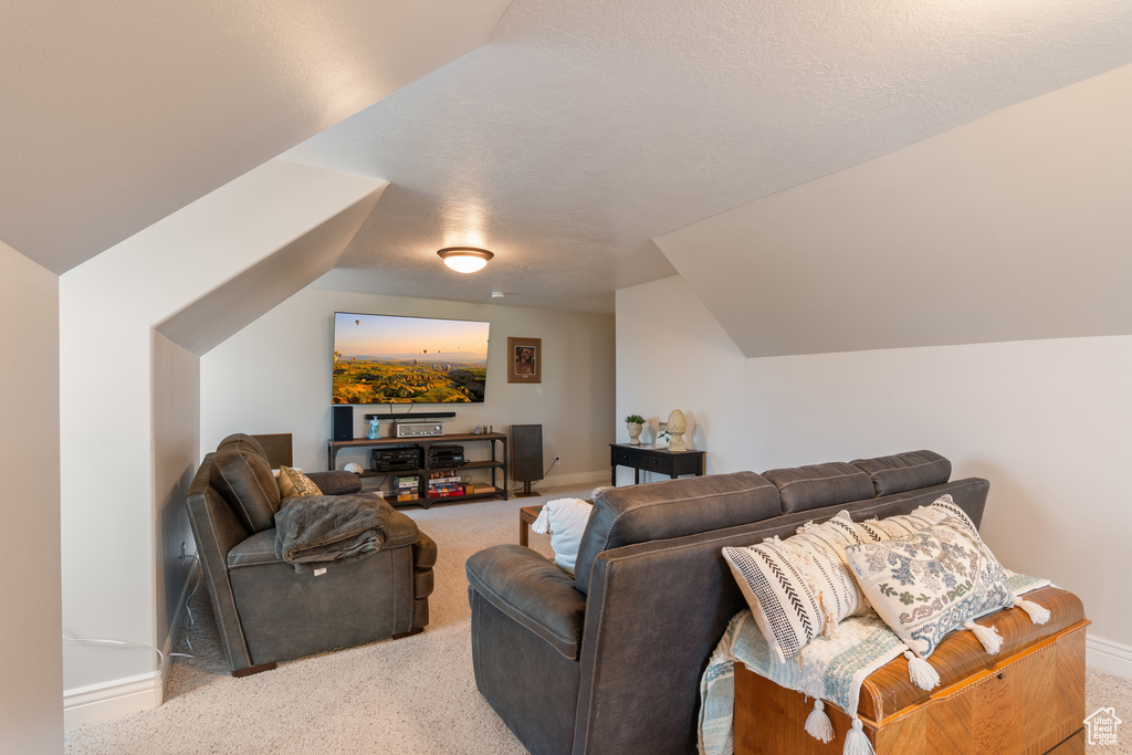 Carpeted living room featuring baseboards and lofted ceiling