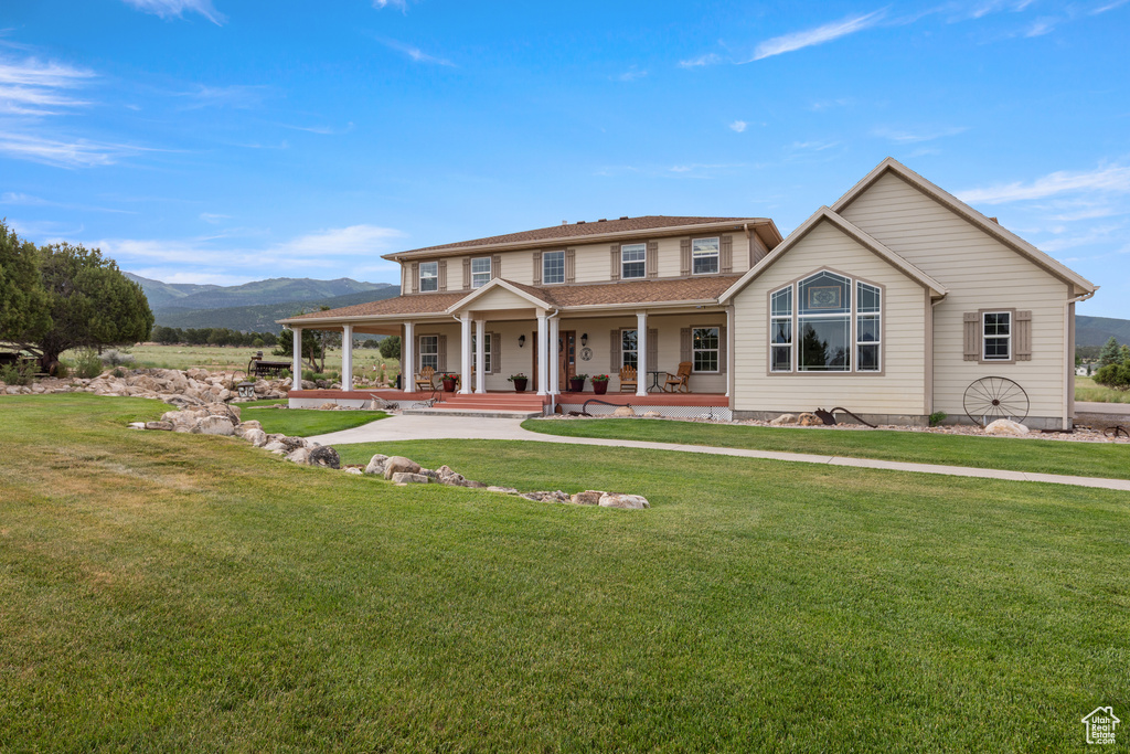View of front of house featuring covered porch, a mountain view, and a front yard