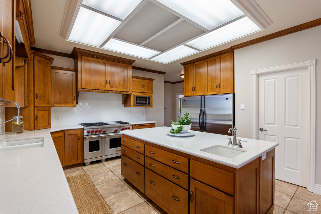 Kitchen featuring stainless steel appliances, crown molding, a kitchen island with sink, brown cabinets, and backsplash