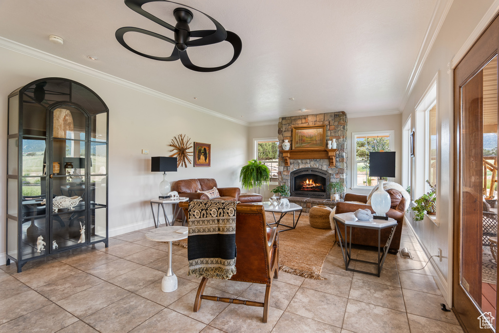 Living area with light tile patterned floors, ornamental molding, a fireplace, and ceiling fan