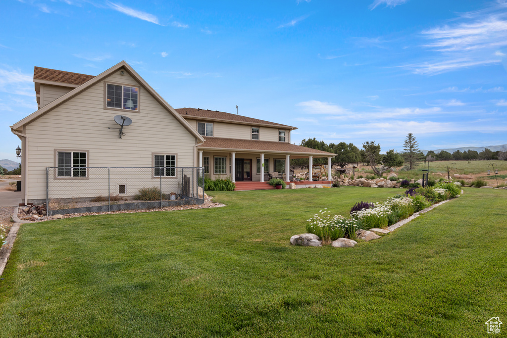 Rear view of property with covered porch and a lawn