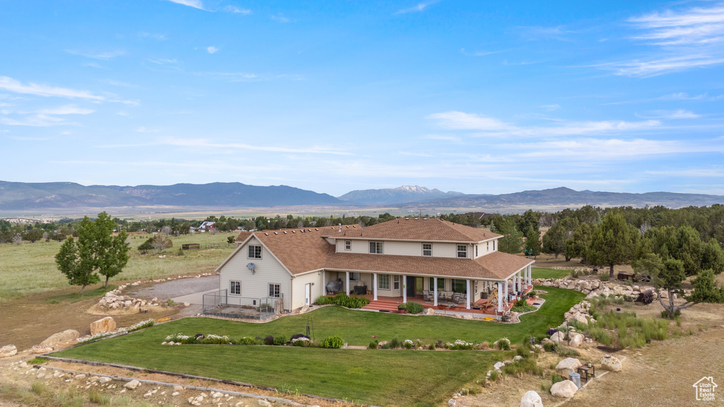 View of front facade with a porch, a mountain view, a front lawn, and dirt driveway