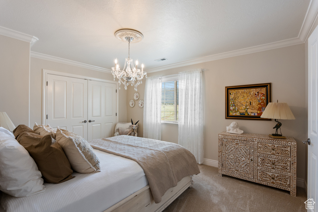 Carpeted bedroom featuring ornamental molding, a chandelier, and a closet