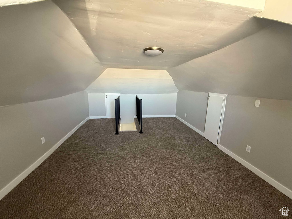 Bonus room with dark carpet and lofted ceiling