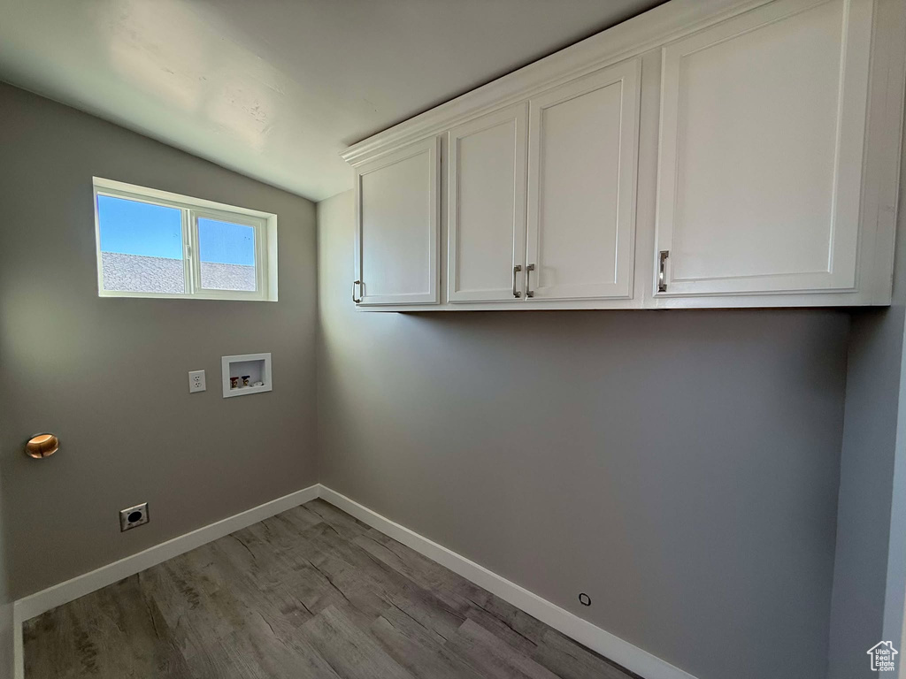 Clothes washing area featuring cabinets, hookup for a washing machine, light hardwood / wood-style flooring, and hookup for an electric dryer