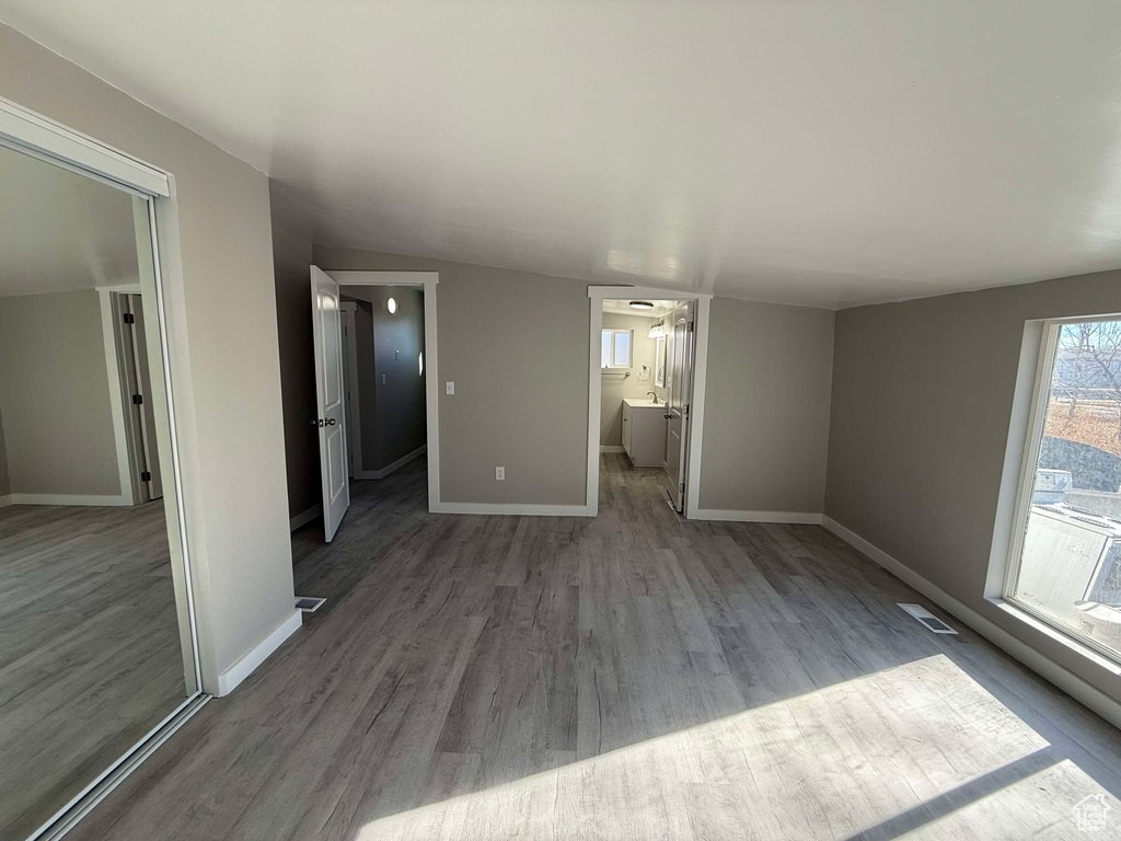 Interior space with ensuite bath, hardwood / wood-style floors, and vaulted ceiling