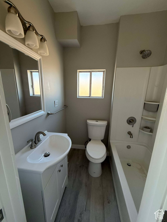 Full bathroom with toilet, plenty of natural light, wood-type flooring, and vanity