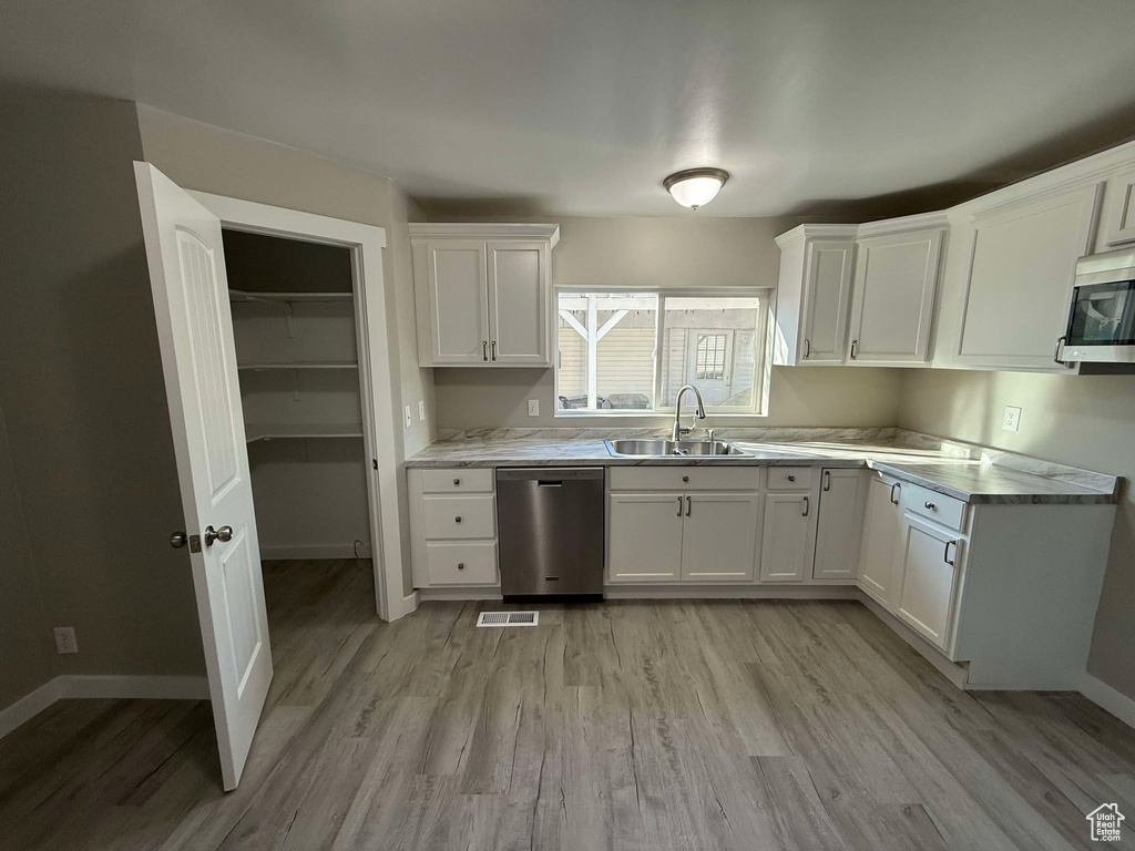 Kitchen featuring sink, white cabinets, light hardwood / wood-style floors, and appliances with stainless steel finishes