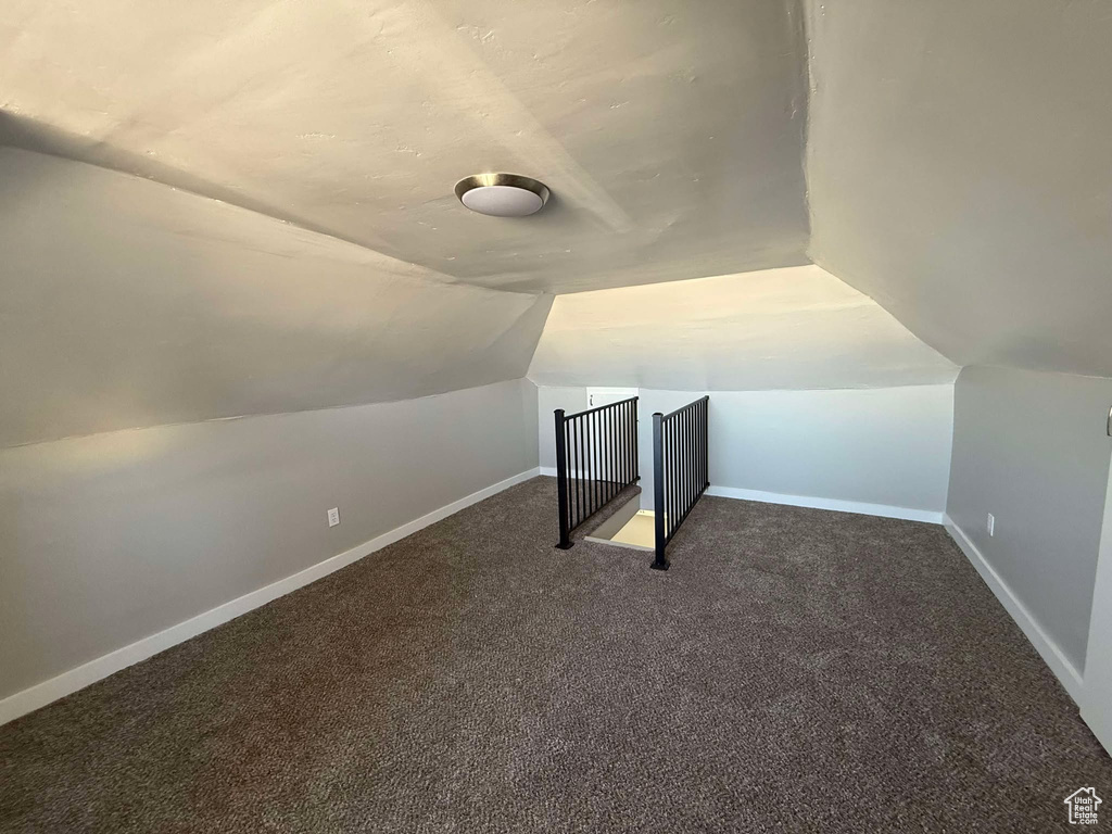 Additional living space featuring lofted ceiling and dark colored carpet