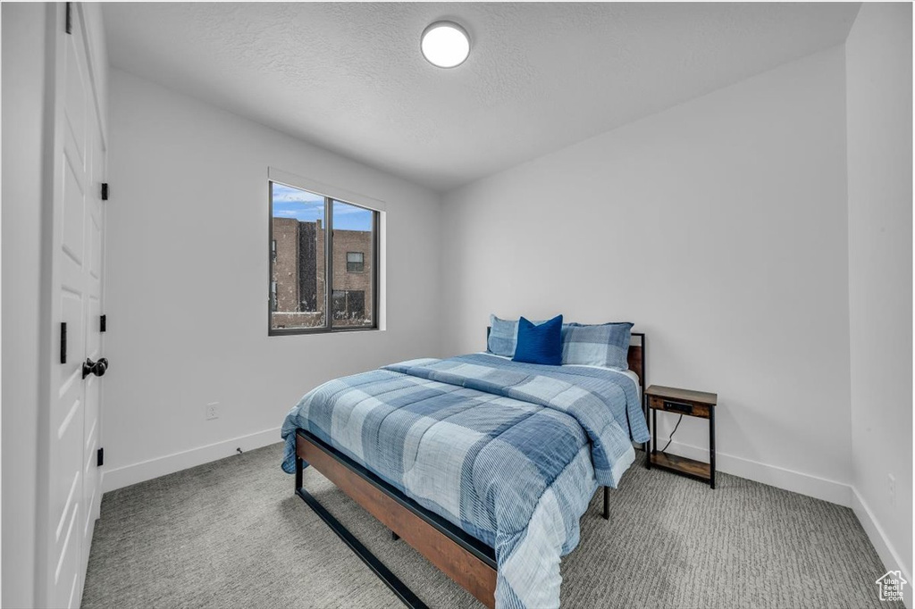 Bedroom with baseboards, carpet, and a textured ceiling