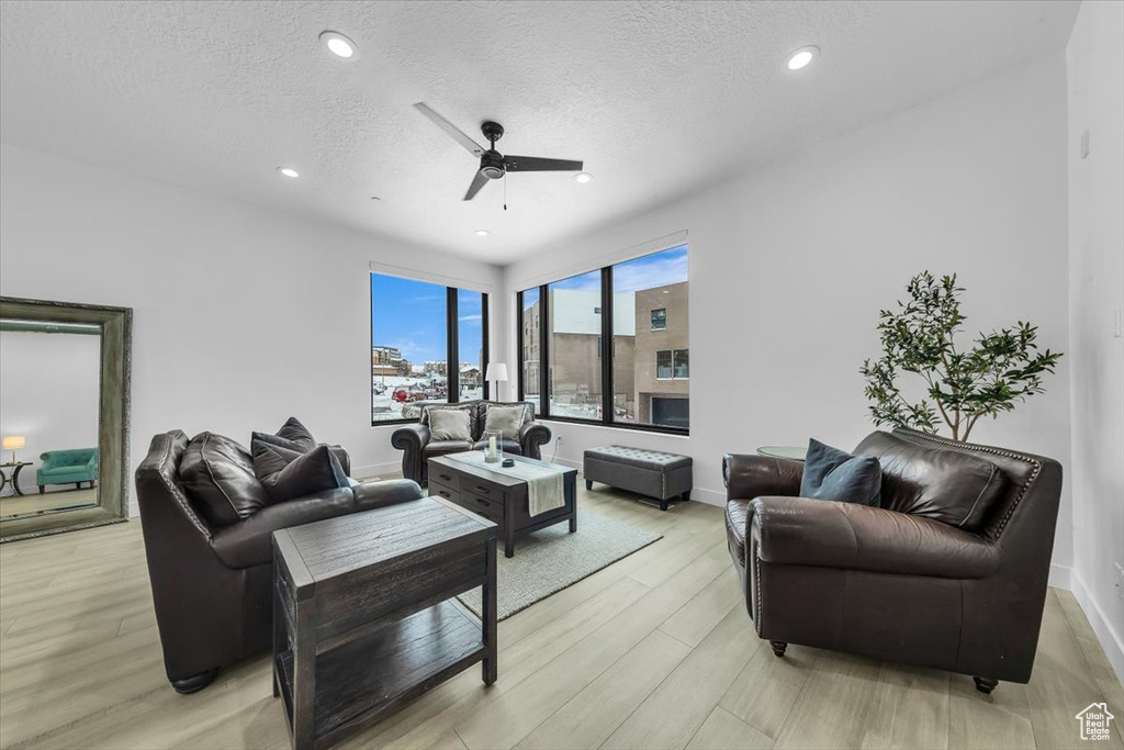 Living room featuring light wood-style flooring, a textured ceiling, recessed lighting, baseboards, and ceiling fan