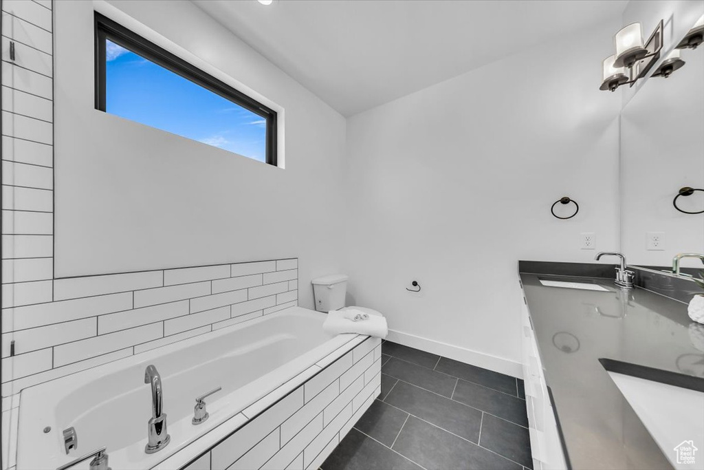 Full bath featuring a sink, baseboards, a garden tub, and tile patterned flooring