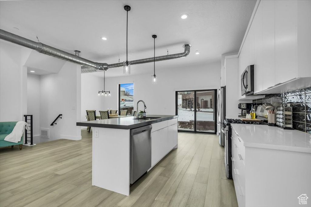 Kitchen with a sink, a kitchen island with sink, appliances with stainless steel finishes, and white cabinets