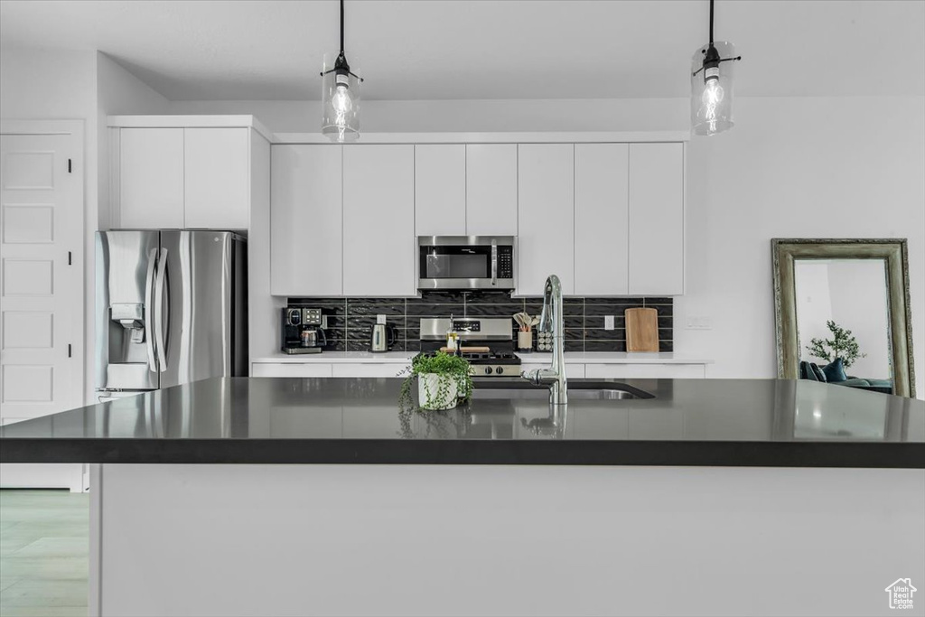Kitchen with a sink, stainless steel appliances, dark countertops, and decorative backsplash