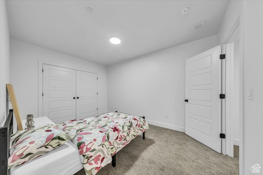 Carpeted bedroom with baseboards, visible vents, and a closet