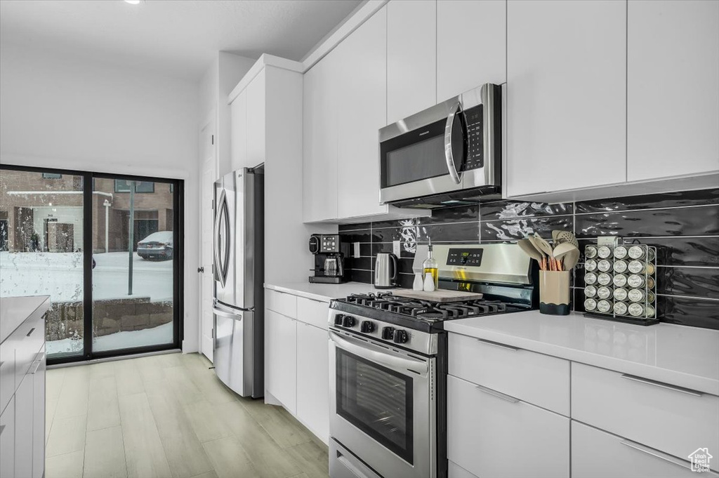 Kitchen featuring light countertops, white cabinets, and appliances with stainless steel finishes