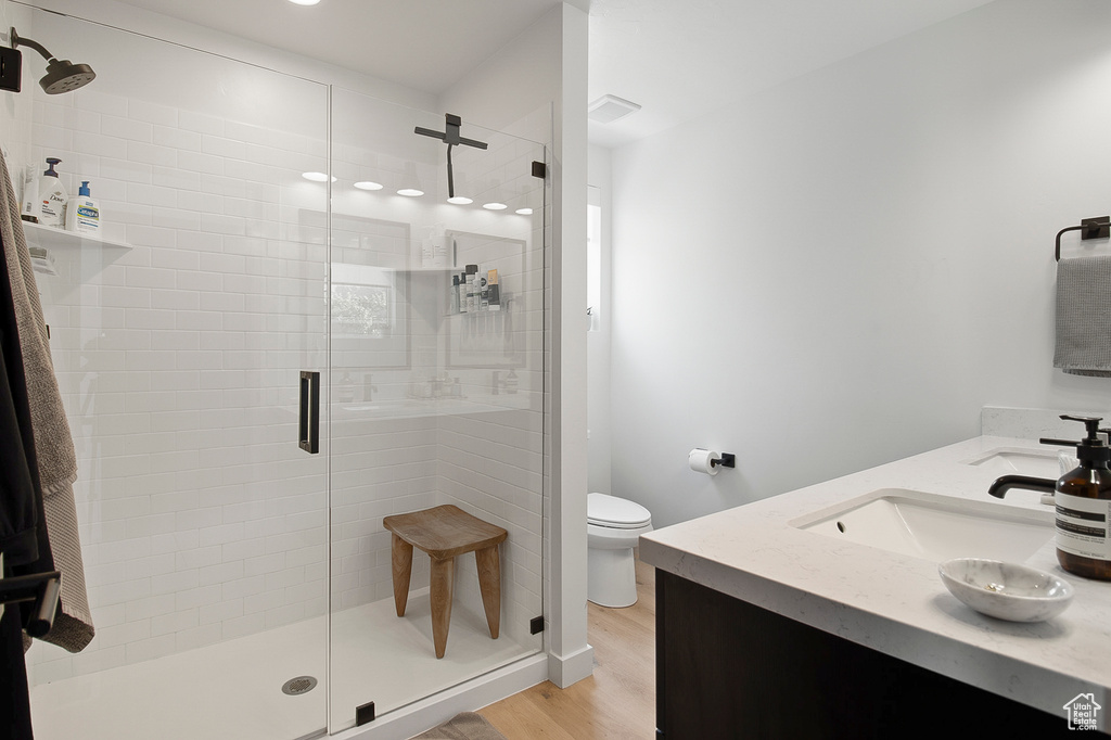 Bathroom with hardwood / wood-style floors, vanity, toilet, and a shower with shower door