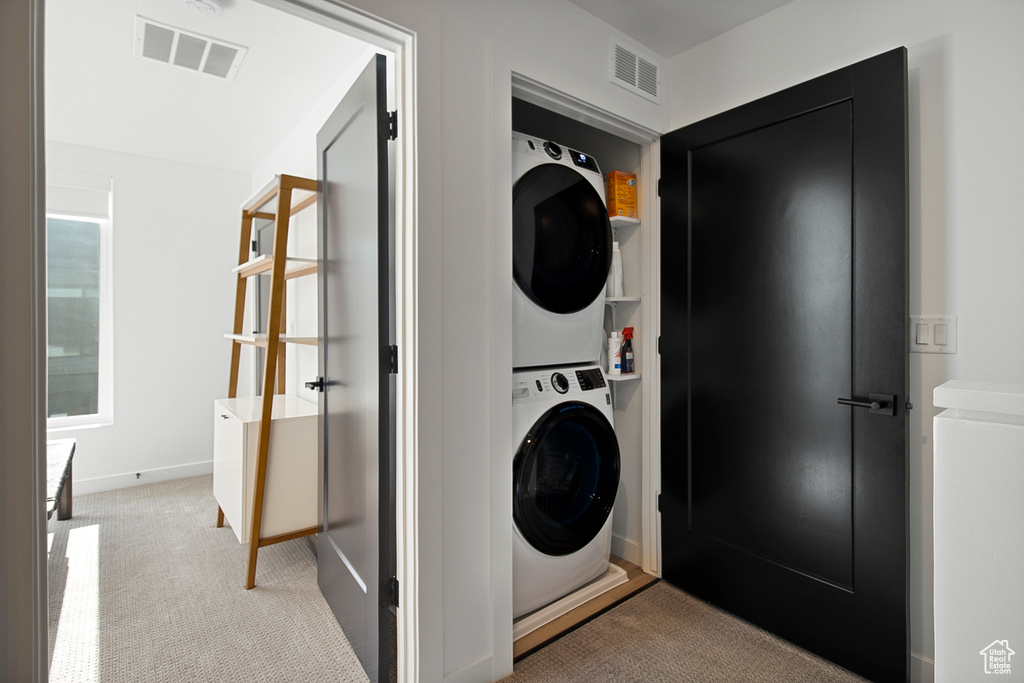 Laundry room featuring light colored carpet and stacked washer and clothes dryer