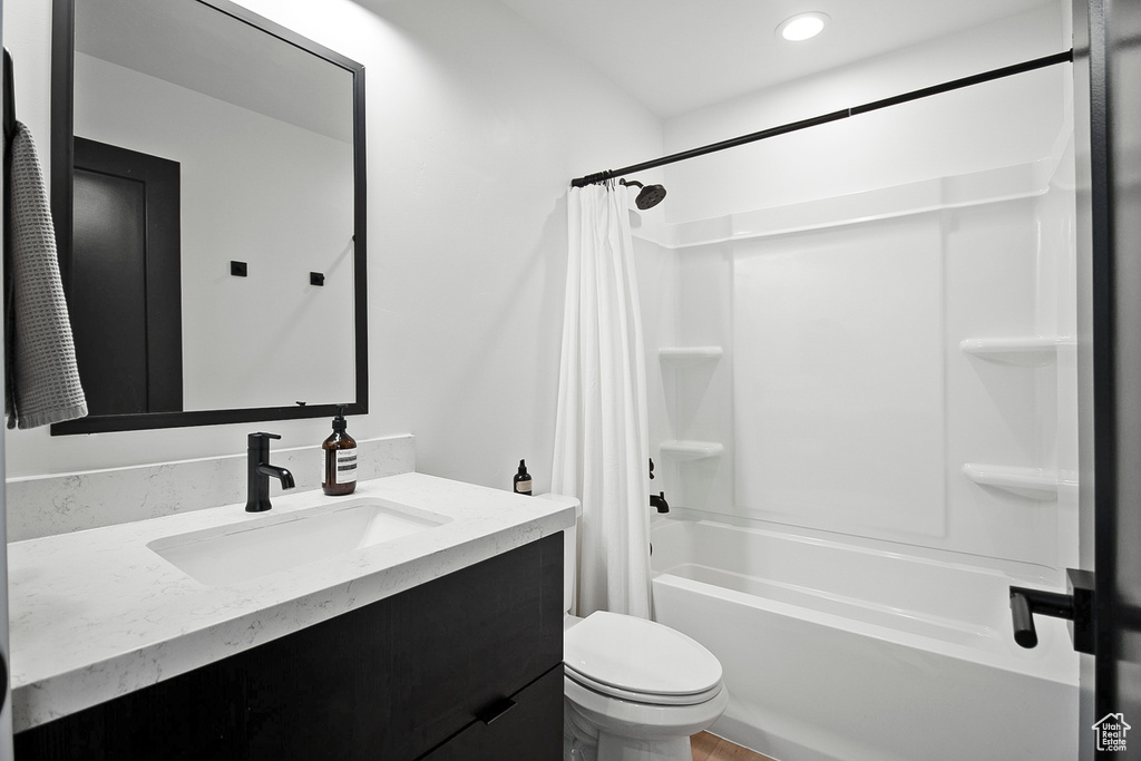 Full bathroom with vanity, shower / bathtub combination with curtain, and toilet