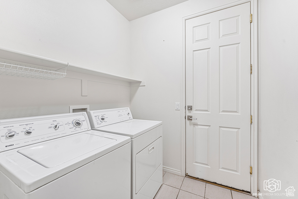 Washroom featuring washer and clothes dryer and light tile patterned flooring