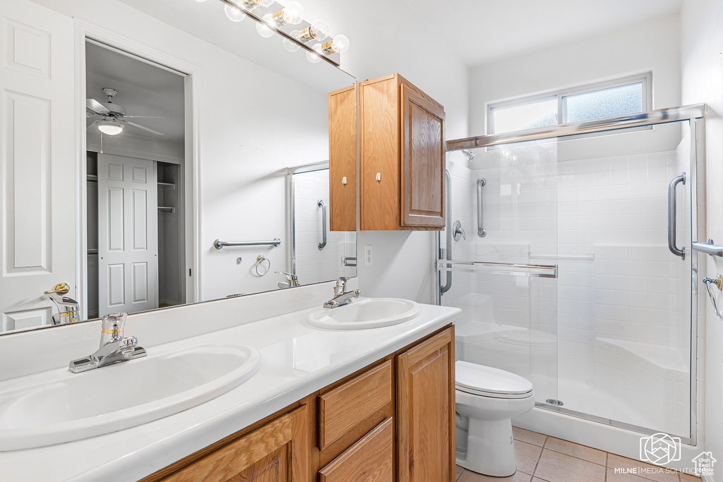 Bathroom with vanity, tile patterned flooring, ceiling fan, toilet, and a shower with shower door