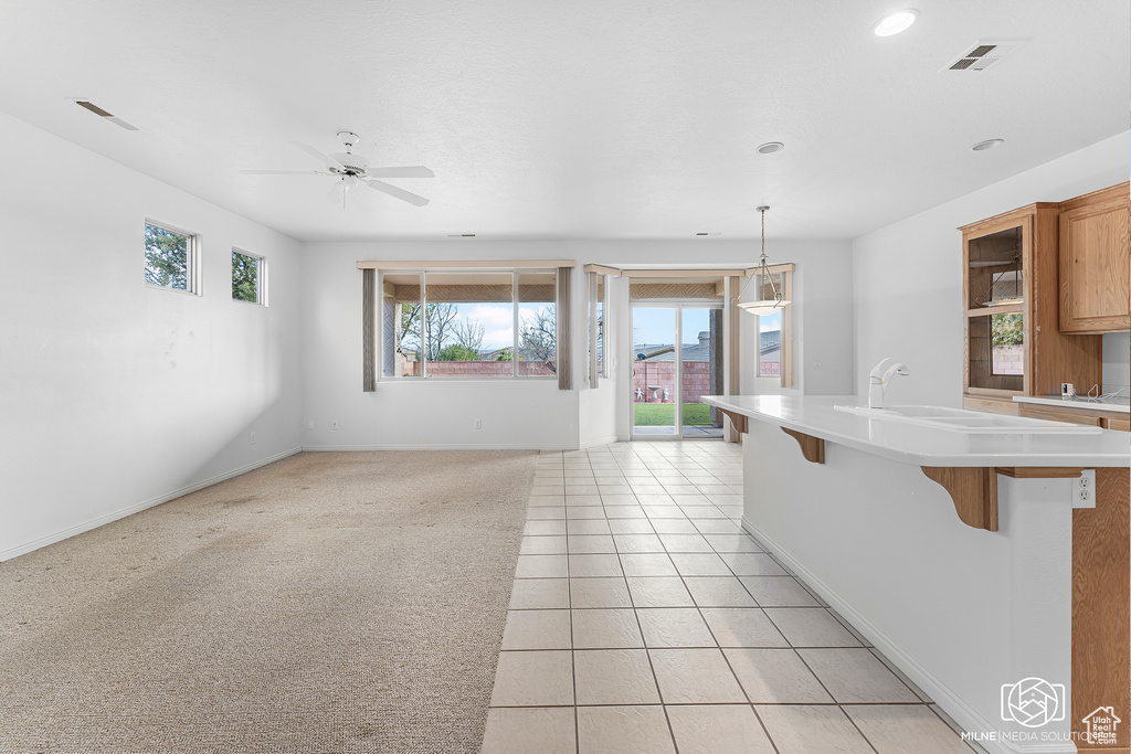 Kitchen featuring ceiling fan, a breakfast bar, light tile patterned floors, and decorative light fixtures