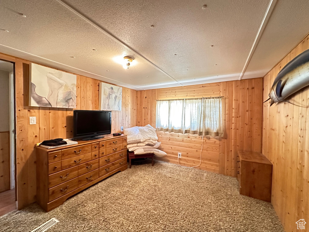 Carpeted bedroom featuring wood walls, log walls, and a textured ceiling