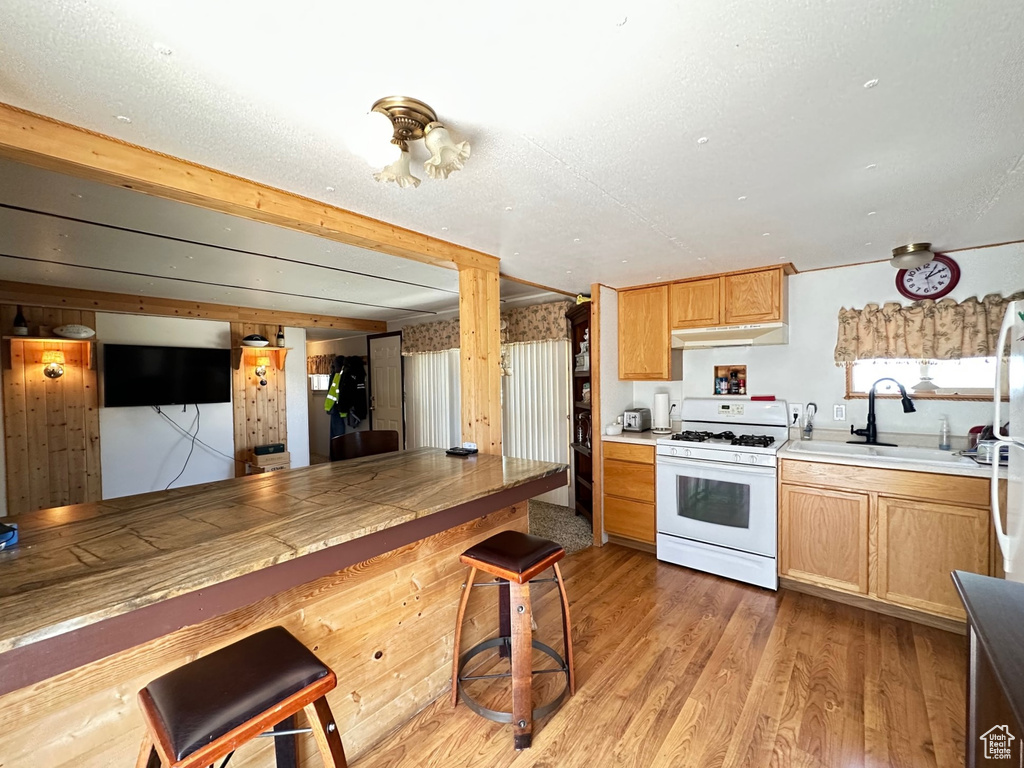 Kitchen featuring white range with gas cooktop, sink, and light hardwood / wood-style flooring