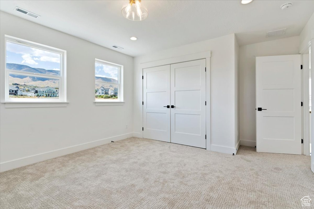 Unfurnished bedroom with light carpet and a closet