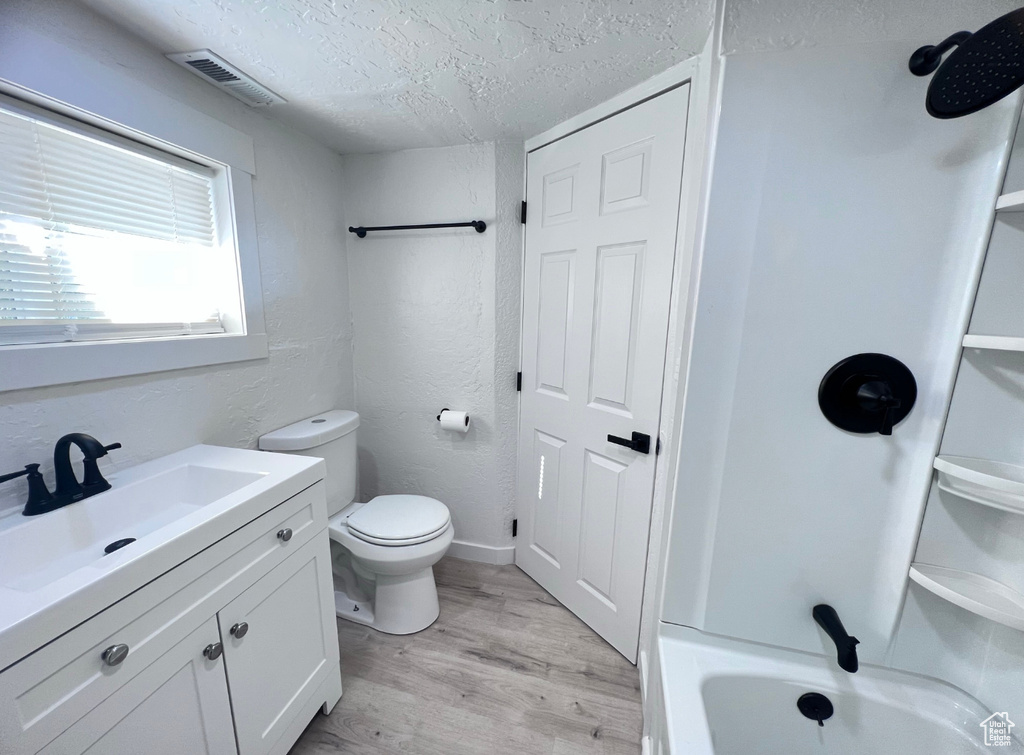 Bathroom with hardwood / wood-style floors, vanity, a textured ceiling, and toilet