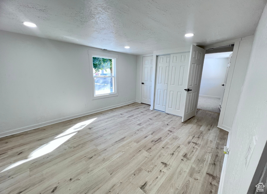 Unfurnished bedroom featuring light wood-type flooring and a textured ceiling