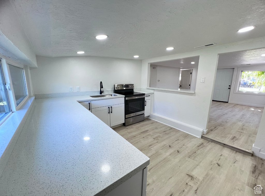 Kitchen with white cabinets, a textured ceiling, sink, and electric stove