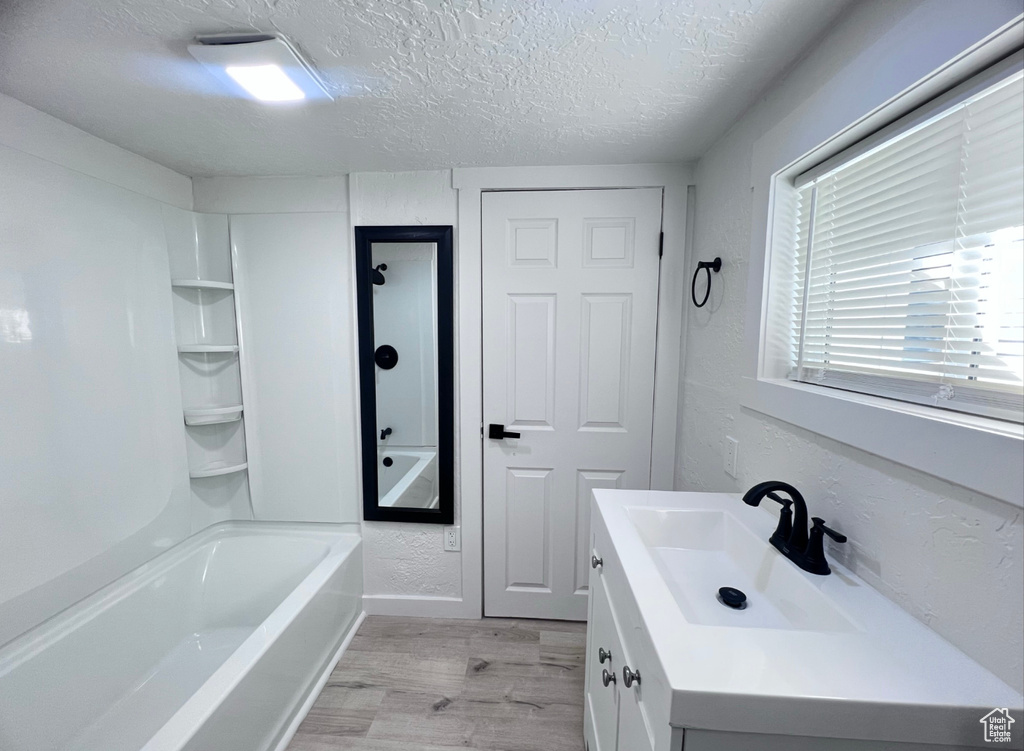 Bathroom featuring vanity, a textured ceiling, hardwood / wood-style flooring, and shower / bathtub combination