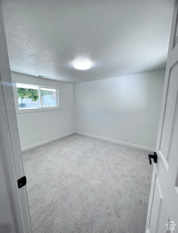 Carpeted empty room with a textured ceiling