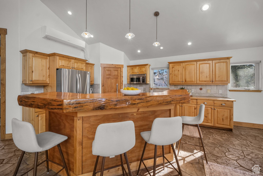 Kitchen with decorative light fixtures, a center island, a kitchen bar, decorative backsplash, and stainless steel appliances