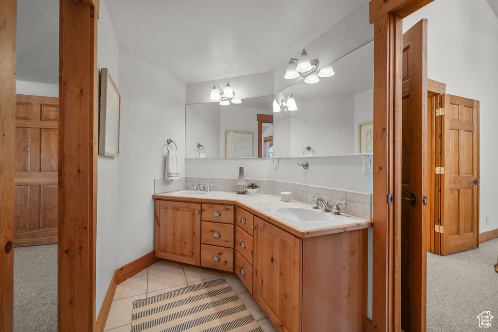 Bathroom featuring tile patterned floors, vanity, and a notable chandelier