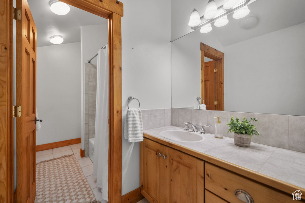 Bathroom featuring shower / bath combo with shower curtain, tile patterned floors, and vanity