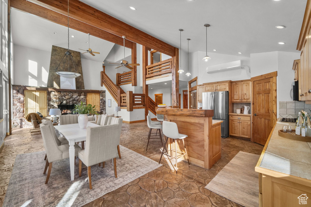 Dining room featuring high vaulted ceiling, ceiling fan, a fireplace, and beamed ceiling