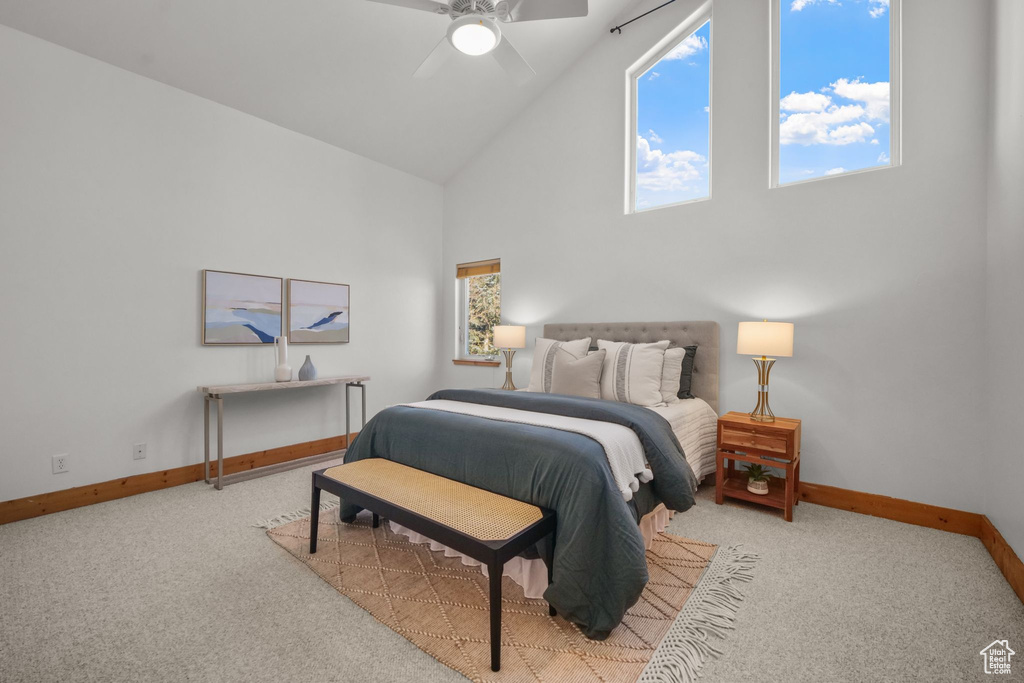 Bedroom with ceiling fan, high vaulted ceiling, and light carpet